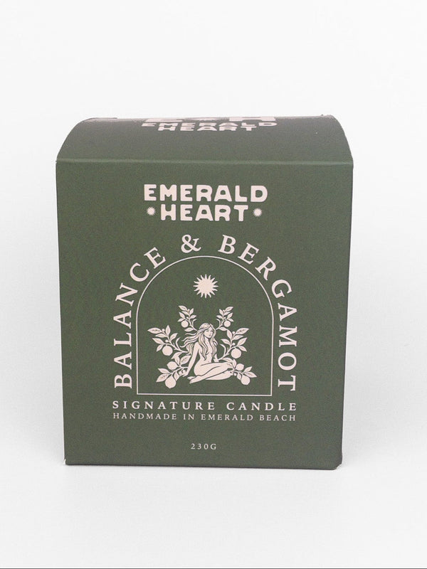 Emerald Heart Balance & Bergamot signature candle in a dark green rectangular box with white text and illustration, set against a plain white background.